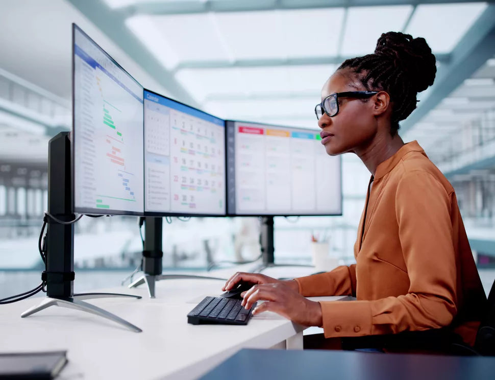 A business user working across calendar and project apps on three monitors