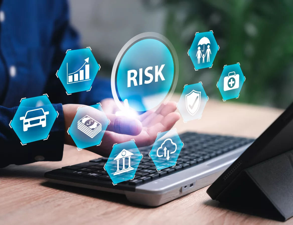 Risk assessment icons above a hand at a laptop, representing a business risk and cloud audit
